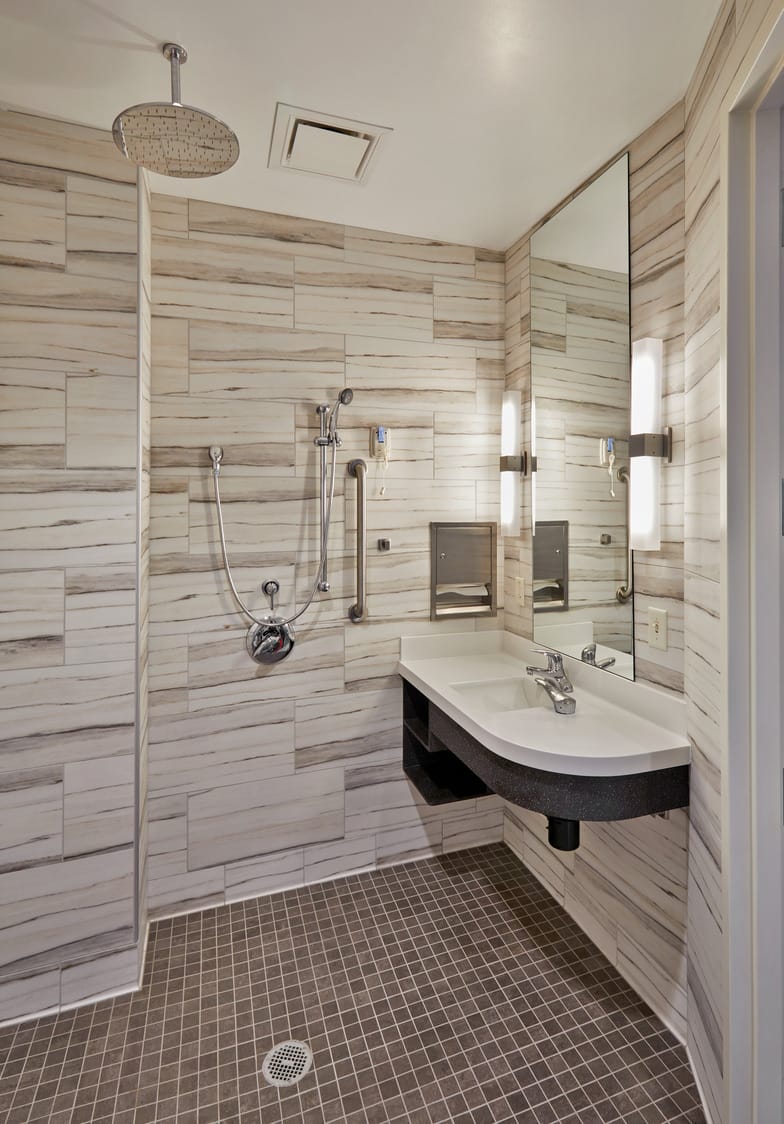 This image shows Indiana Spine Hospital's inpatient private bathrooms, a spa-like luxury bathroom with floor-to-ceiling tile and a standing shower for enhanced patient safety. This image shows BSA's expertise in interior design, specifically our expertise in designing patient-centered spaces for patients who have just undergone an operation to the spine