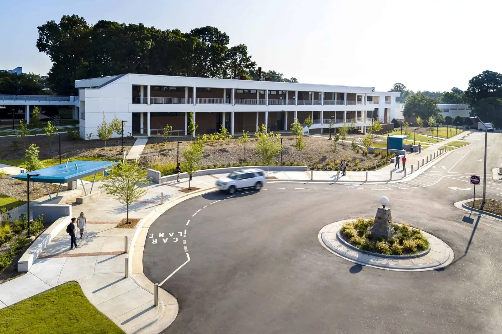Aerial view of the entrance to the Wake Tech campus featuring a roundabout entrance. There are two bright blue bus shelters with modern, angular designs. Between the two stops is a clear 