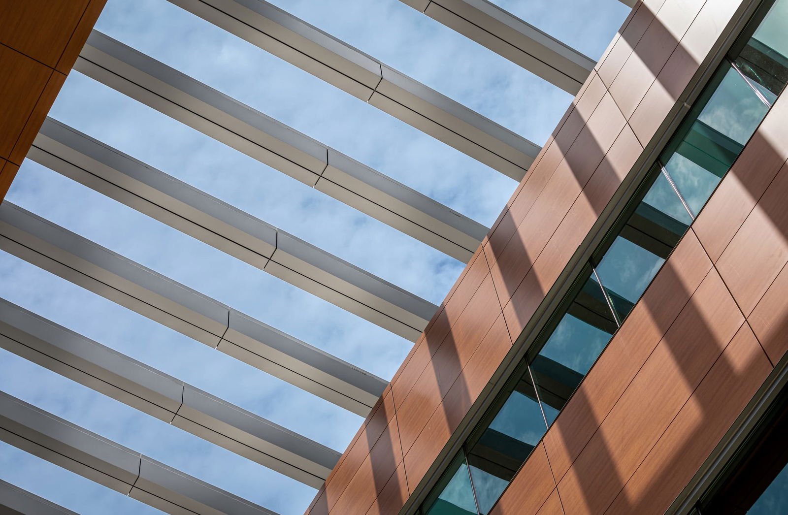 Close up of the exterior architectural elements of the UCHealth Greeley Hospital, including a sleek wooden-paneled wall with large windows and large metal beams supporting the structure.